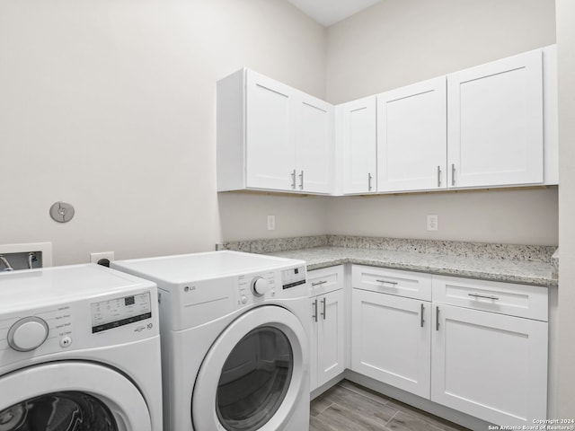 washroom featuring washing machine and dryer, cabinet space, and light wood-style floors