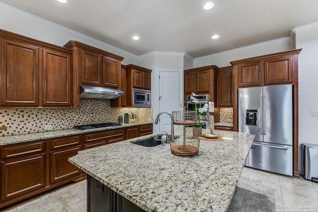 kitchen with light stone countertops, under cabinet range hood, appliances with stainless steel finishes, and a sink