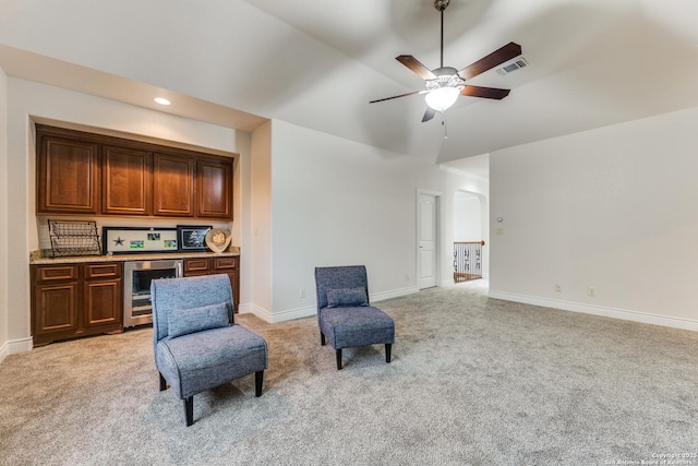 living area featuring beverage cooler, visible vents, baseboards, and light colored carpet