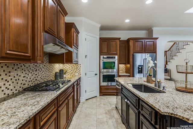 kitchen featuring light stone counters, ornamental molding, stainless steel appliances, under cabinet range hood, and a sink