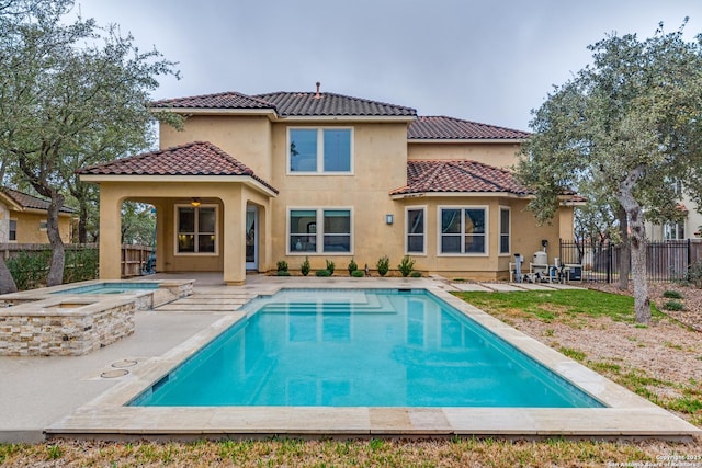 back of property with stucco siding, a fenced backyard, a patio area, and an in ground hot tub