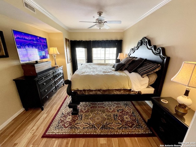 bedroom featuring visible vents, crown molding, and wood finished floors