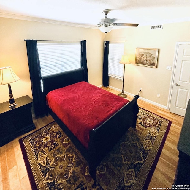 bedroom with visible vents, crown molding, baseboards, and wood finished floors