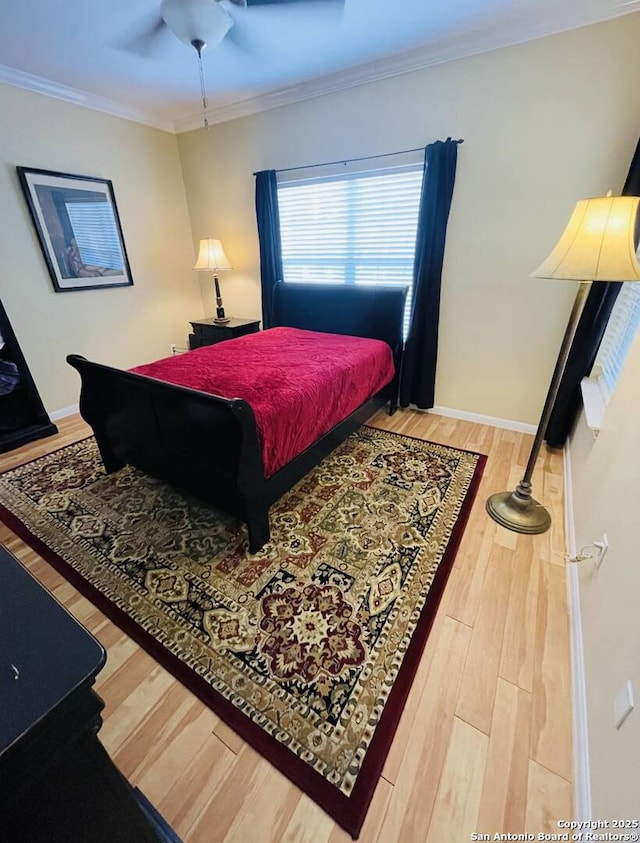 bedroom with ornamental molding, a ceiling fan, baseboards, and wood finished floors