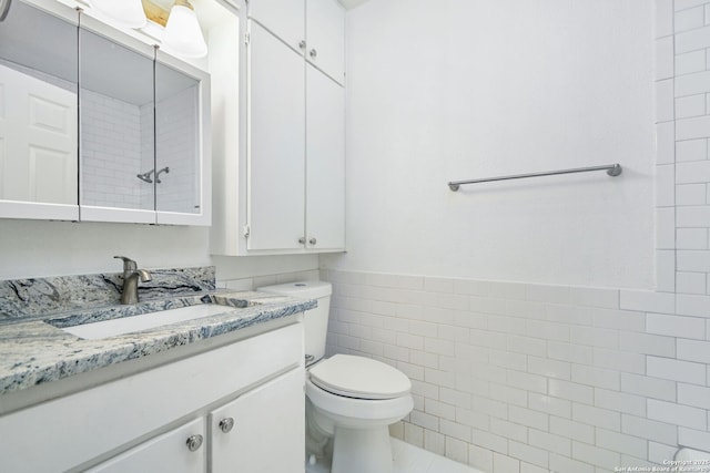 bathroom featuring toilet, wainscoting, tile walls, and vanity