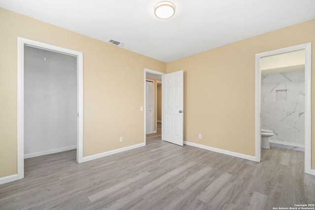 unfurnished bedroom featuring a closet, visible vents, connected bathroom, wood finished floors, and baseboards