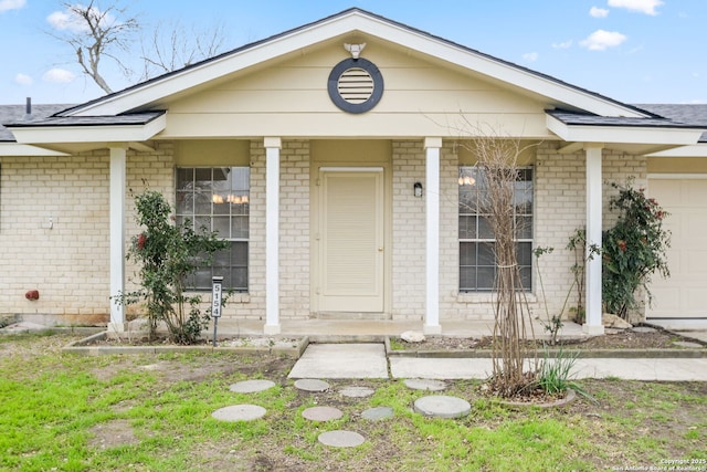 view of exterior entry featuring a garage and covered porch