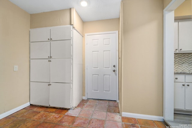 interior space with light countertops, tasteful backsplash, white cabinetry, and baseboards