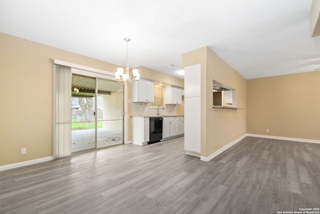 unfurnished living room with a chandelier, wood finished floors, and baseboards