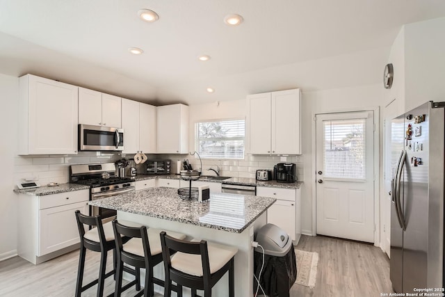 kitchen featuring a healthy amount of sunlight, light stone countertops, tasteful backsplash, and stainless steel appliances