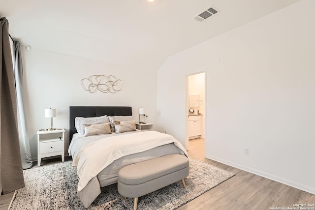 bedroom with light wood-type flooring, connected bathroom, visible vents, and baseboards