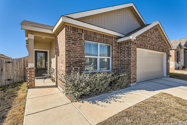 view of front of home with a garage, driveway, fence, and brick siding