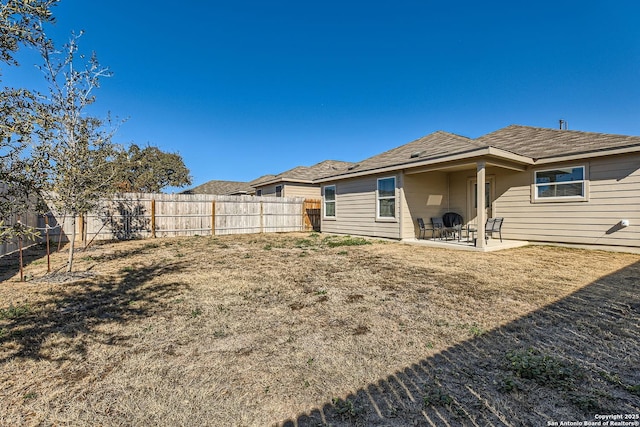 back of property with a yard, a patio area, and a fenced backyard