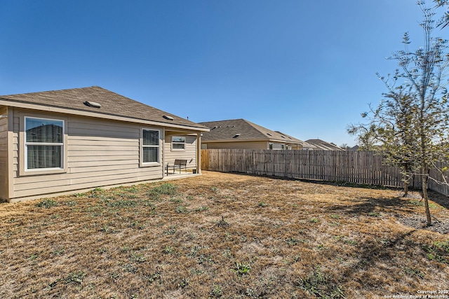 back of house with a fenced backyard and a lawn