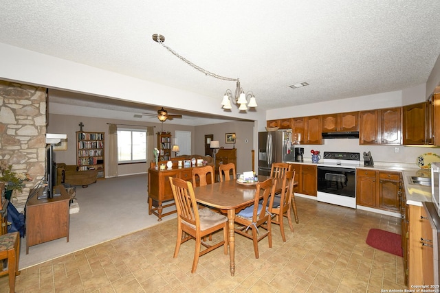 dining space featuring a textured ceiling, ceiling fan with notable chandelier, and visible vents