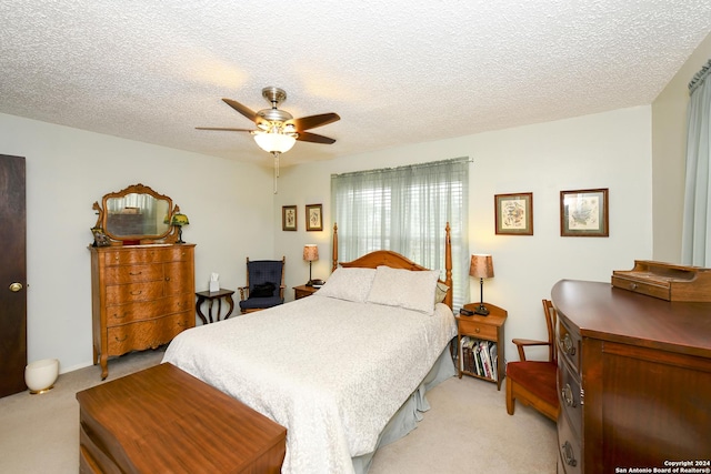 bedroom featuring light carpet, ceiling fan, and a textured ceiling