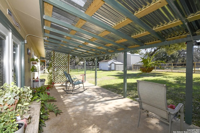 view of patio / terrace featuring a fenced backyard, a storage unit, and an outbuilding