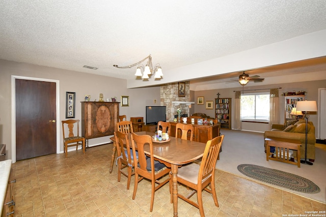 dining space with a textured ceiling, ceiling fan with notable chandelier, and visible vents