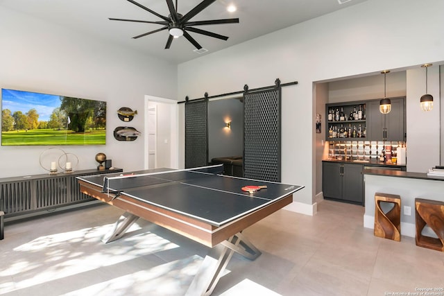 recreation room featuring indoor wet bar, ceiling fan, visible vents, and a barn door