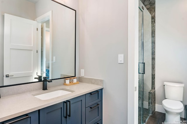 full bathroom with toilet, wood finished floors, vanity, baseboards, and a stall shower