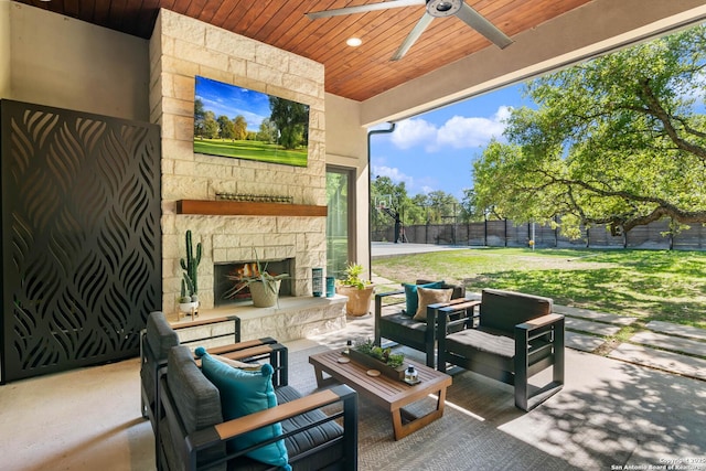 view of patio / terrace featuring an outdoor living space with a fireplace, a fenced backyard, and a ceiling fan