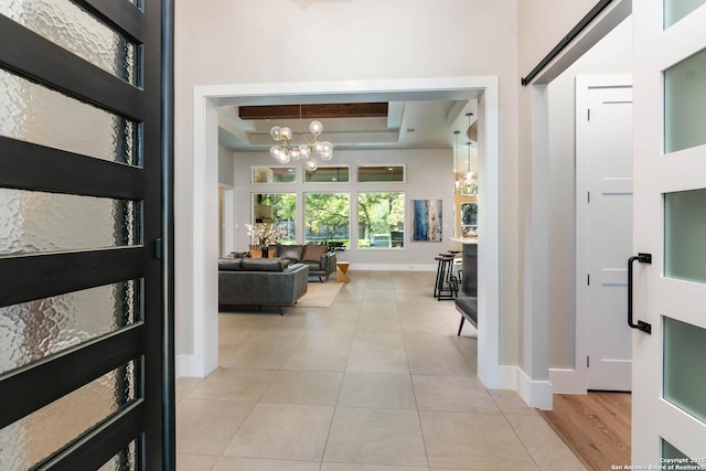 foyer featuring light tile patterned floors, baseboards, a raised ceiling, and a notable chandelier