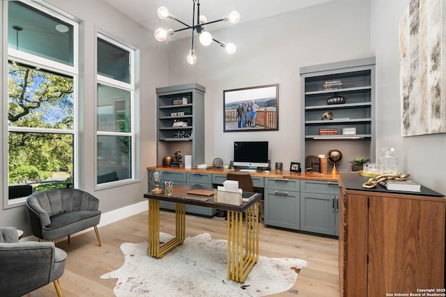 office space with baseboards, light wood finished floors, and a notable chandelier