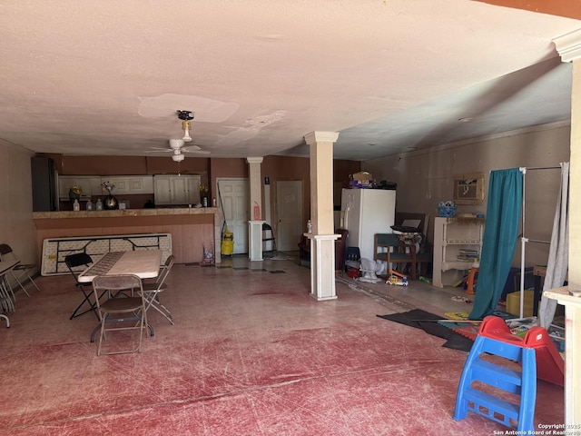 below grade area with a textured ceiling, tile patterned floors, freestanding refrigerator, and a ceiling fan