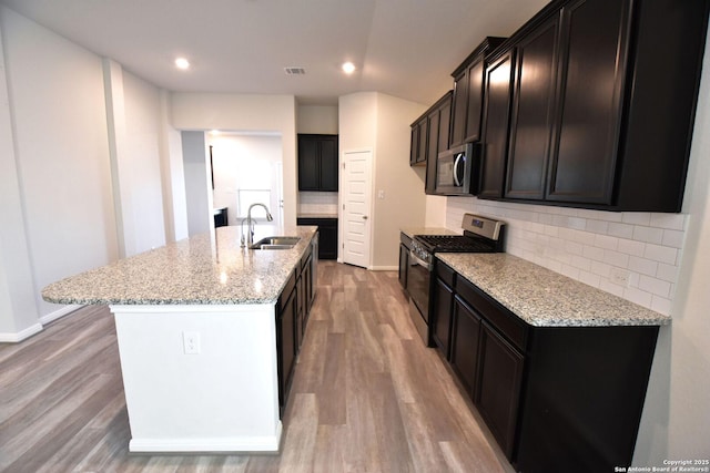 kitchen with appliances with stainless steel finishes, a sink, visible vents, and light stone countertops