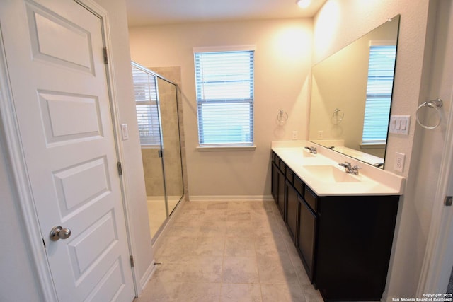 full bathroom featuring double vanity, a stall shower, baseboards, and a sink