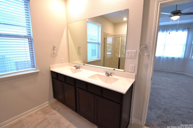 bathroom with double vanity, a stall shower, baseboards, and a sink