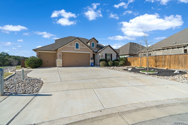 view of front of house with driveway, a garage, stone siding, fence, and stucco siding