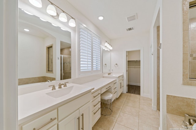 bathroom with a walk in closet, visible vents, a shower stall, vanity, and tile patterned floors