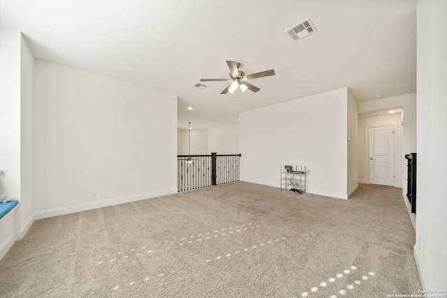 empty room with carpet floors, visible vents, baseboards, and a ceiling fan