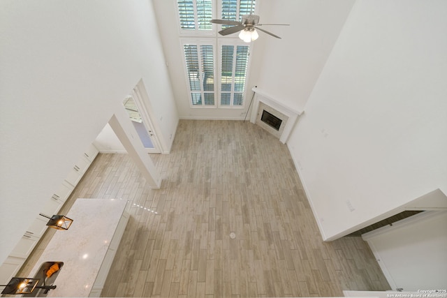 unfurnished living room with visible vents, a ceiling fan, a towering ceiling, wood finished floors, and a fireplace