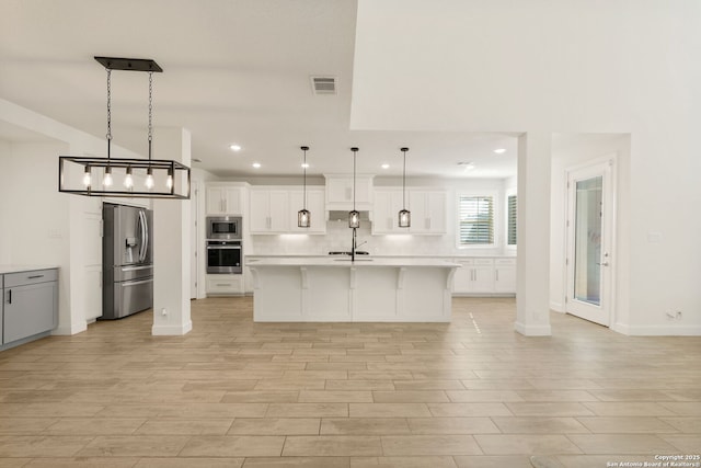 kitchen featuring a breakfast bar area, stainless steel appliances, visible vents, light wood-style floors, and light countertops