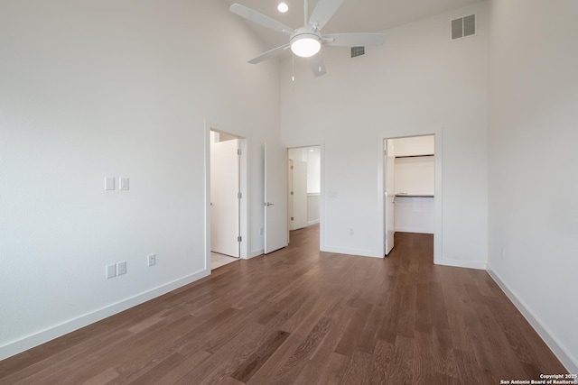 unfurnished bedroom with dark wood-type flooring, a walk in closet, visible vents, and baseboards