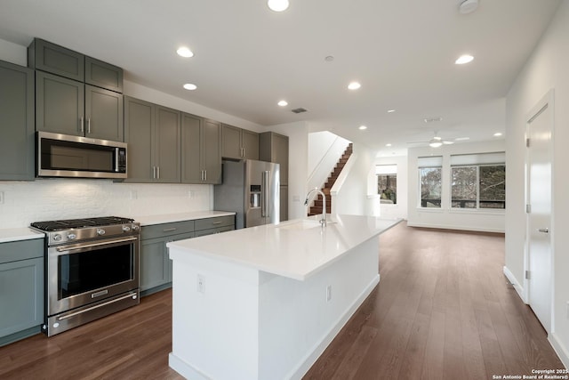 kitchen featuring appliances with stainless steel finishes, dark wood-style flooring, a sink, and tasteful backsplash