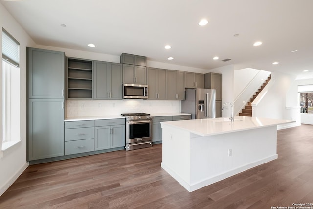 kitchen with wood finished floors, premium appliances, a sink, and gray cabinetry