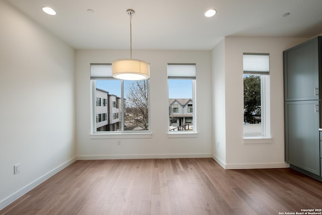 unfurnished dining area with baseboards, wood finished floors, and a healthy amount of sunlight