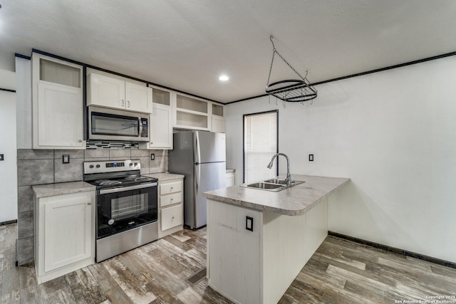 kitchen featuring stainless steel appliances, wood finished floors, open shelves, and a sink