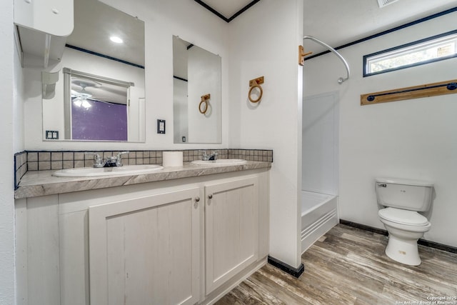 bathroom featuring toilet, shower / bathtub combination, a sink, and wood finished floors