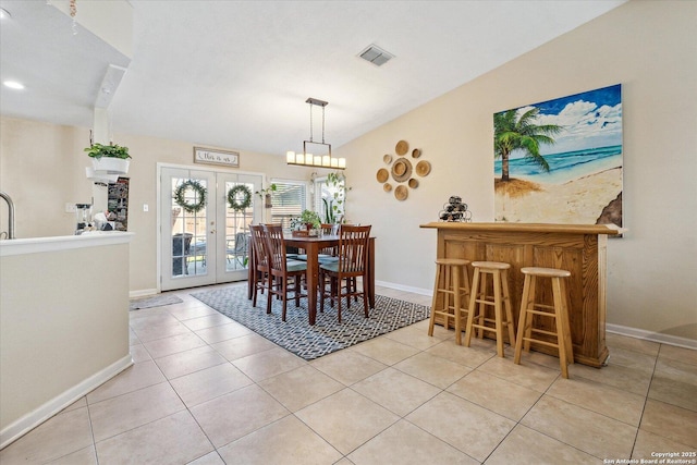 dining room with french doors, a dry bar, visible vents, vaulted ceiling, and tile patterned flooring