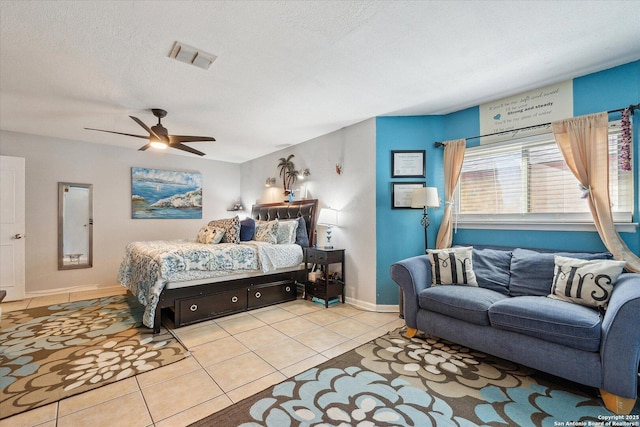 tiled bedroom featuring a textured ceiling, ceiling fan, visible vents, and baseboards