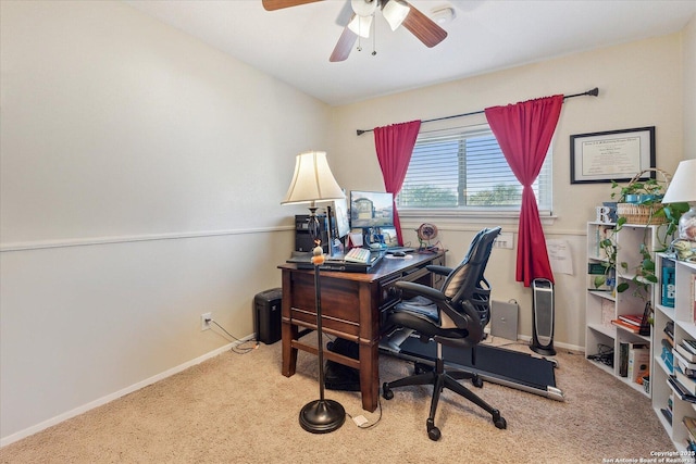 carpeted office space featuring a ceiling fan and baseboards