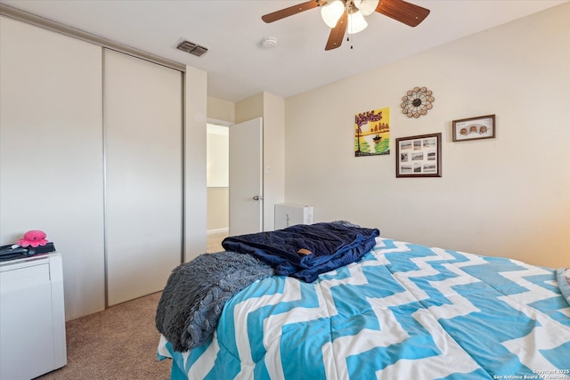 bedroom featuring a ceiling fan, a closet, visible vents, and carpet flooring