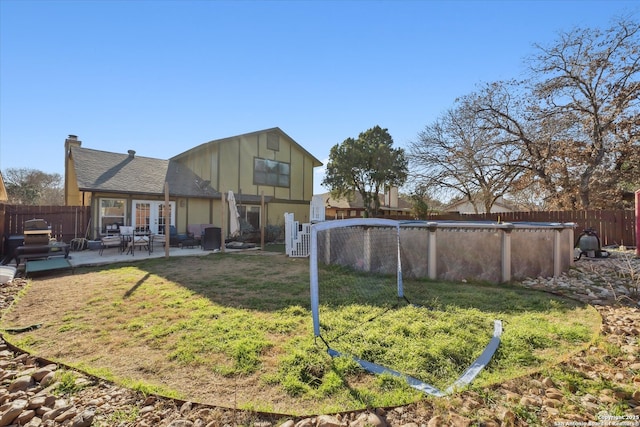 back of house featuring a fenced in pool, a fenced backyard, a yard, and a chimney