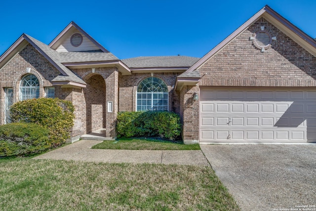 view of front of property with a garage, concrete driveway, brick siding, and roof with shingles