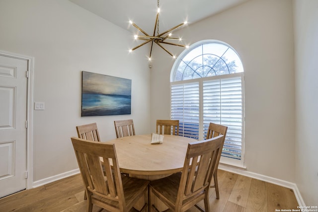 dining area featuring light wood-type flooring, baseboards, and an inviting chandelier