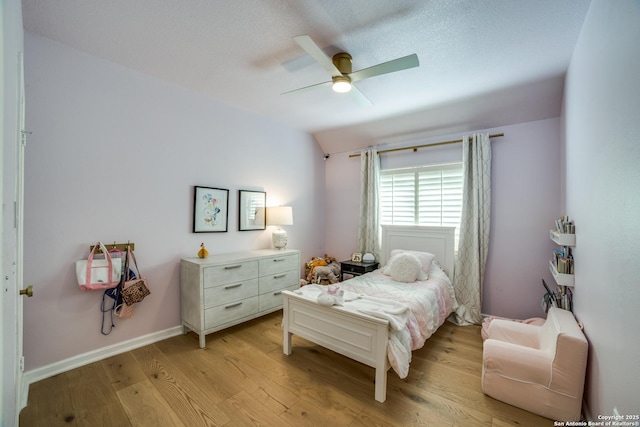 bedroom featuring a ceiling fan, lofted ceiling, baseboards, and light wood finished floors